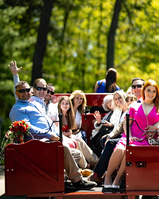 Group of guests enjoying a sunny wagon ride at Preserve Resort & Spa, waving and smiling