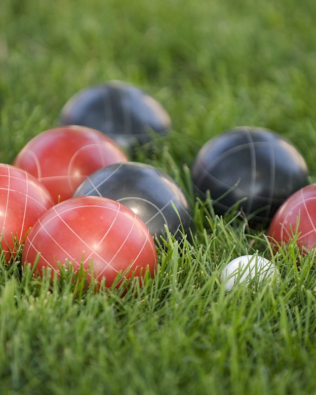 Red and black bocce balls scattered on lush grass at The Preserve Resort & Spa.