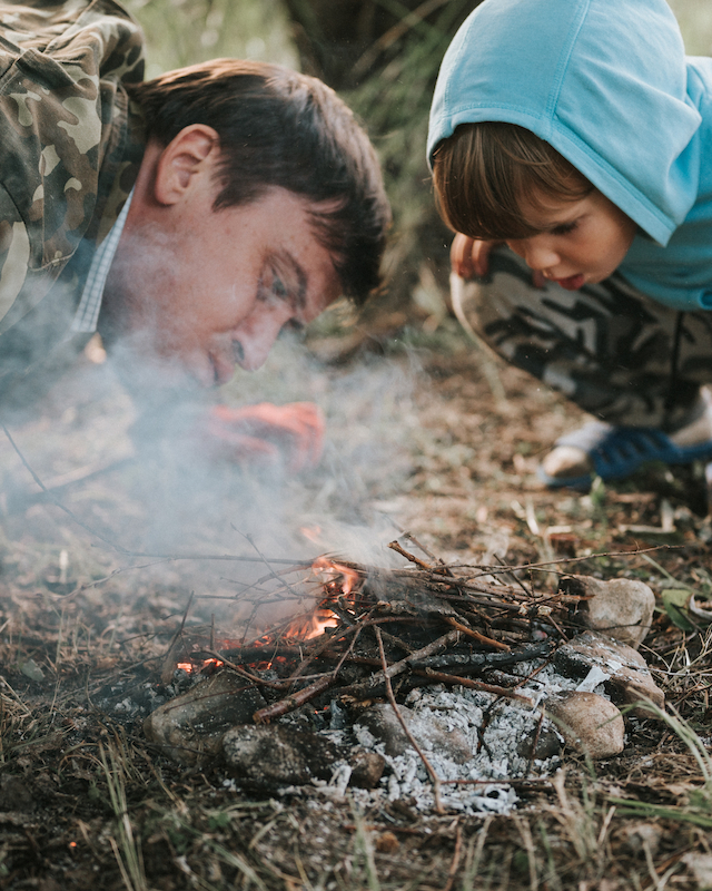 A child learns fire-building techniques at Preserve Resort & Spa, an engaging survival skills activity.