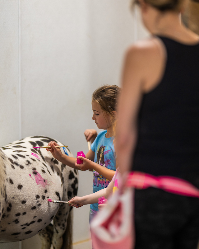Young artist joyfully painting a pony at The Preserve Resort & Spa's Paint the Pony event, full of creativity and fun.