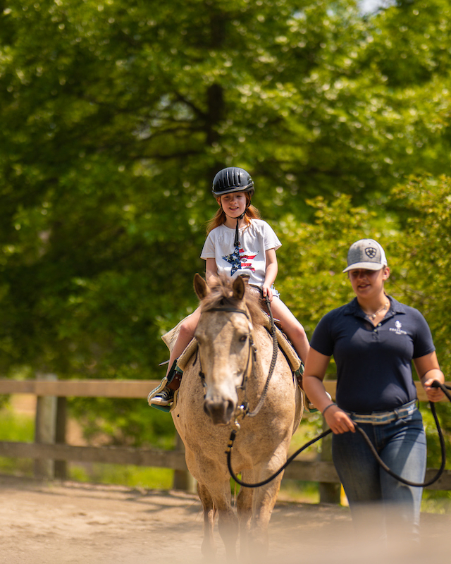 A young rider confidently practices riding at the Pegasus Kids Camp, guided by The Preserve Resort & Spa's expert equestrian staff.