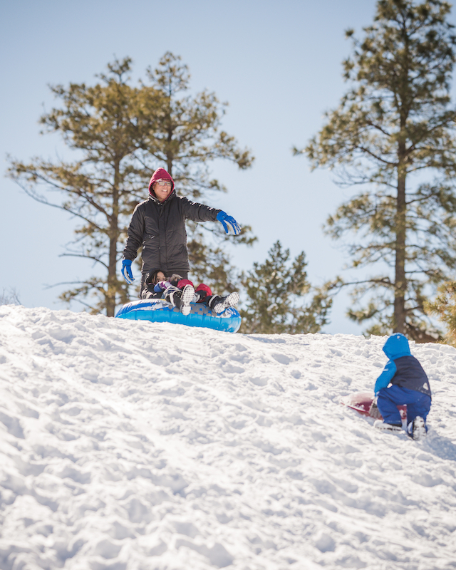 Family prepares for fun at the top of a snowy sledding hill at The Preserve Resort & Spa, excitement in the air.