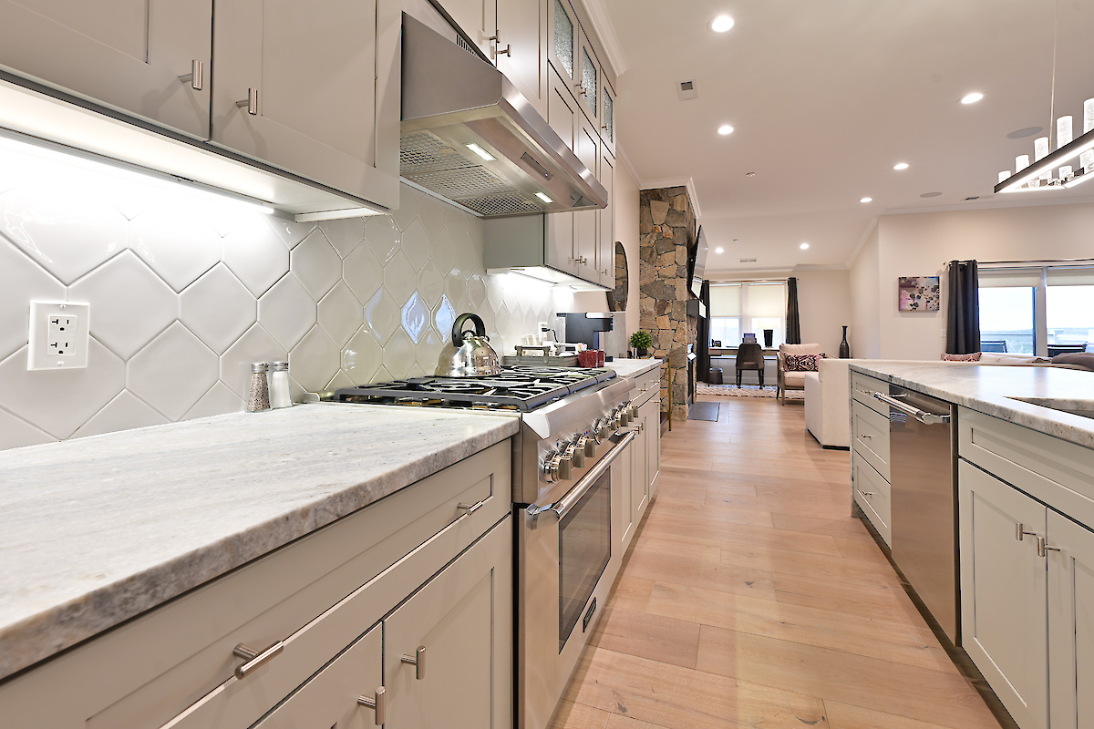 Modern kitchen with stainless steel appliances, white cabinetry, light wood flooring, a central island, and recessed lighting.