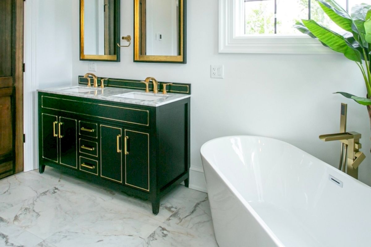 A bathroom features a wooden door, dual-sink vanity with mirrors, a white bathtub, marble floor, and a potted plant near the window.