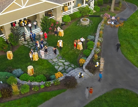 An aerial view of an outdoor event at The Preserve Sporting Club & Resort, featuring guests mingling near a beautifully landscaped garden and elegant pathways.