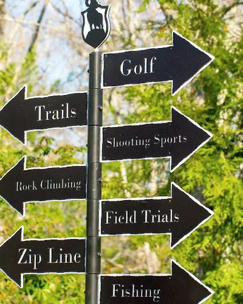 A signpost with arrows points to activities: Golf, Trails, Shooting Sports, Rock Climbing, Field Trials, Zip Line, and Fishing.