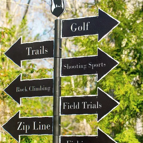 A signpost with arrows points to activities: Golf, Trails, Shooting Sports, Rock Climbing, Field Trials, Zip Line, and Fishing.