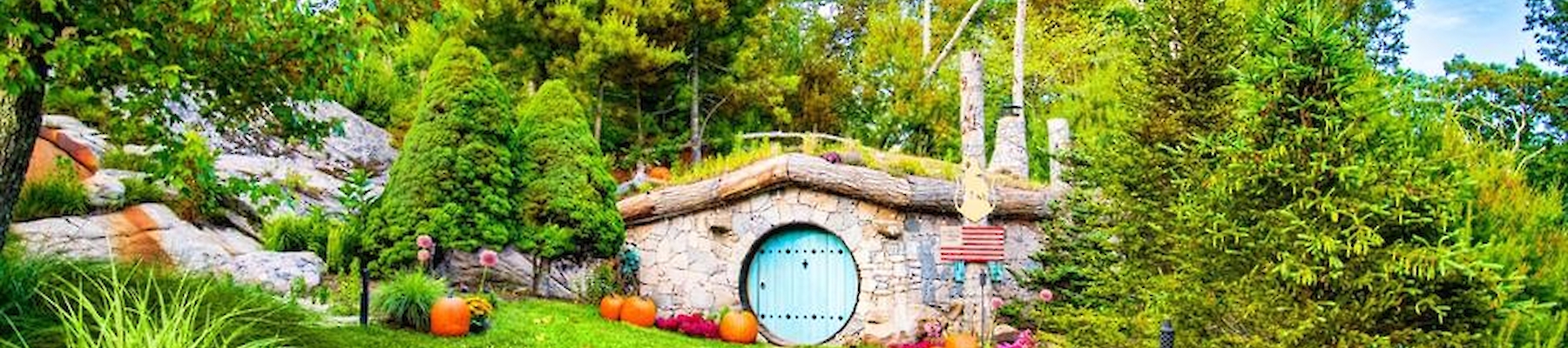 A whimsical garden scene features a round door nestled in a grassy hill, surrounded by trees and autumn leaves, evoking a fairy-tale vibe.