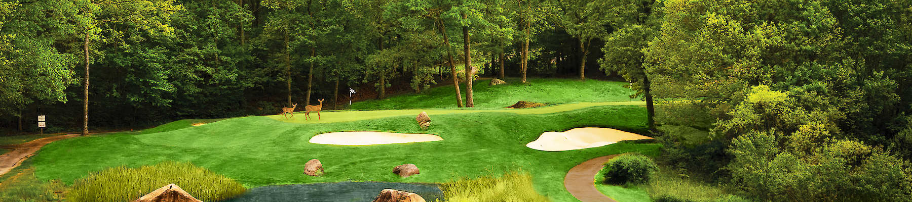 A scenic golf course with a small pond, sand traps, and lush green surroundings under a vibrant sunset sky, surrounded by trees.